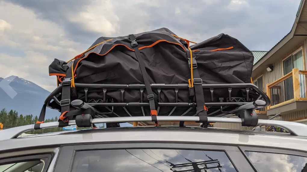 The image shows a MAXXHAUL Cargo Carrier on a Subaru Forester holding big cargo bags for camping. 